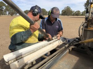 Image of two men undertaking soil testing in a paddock